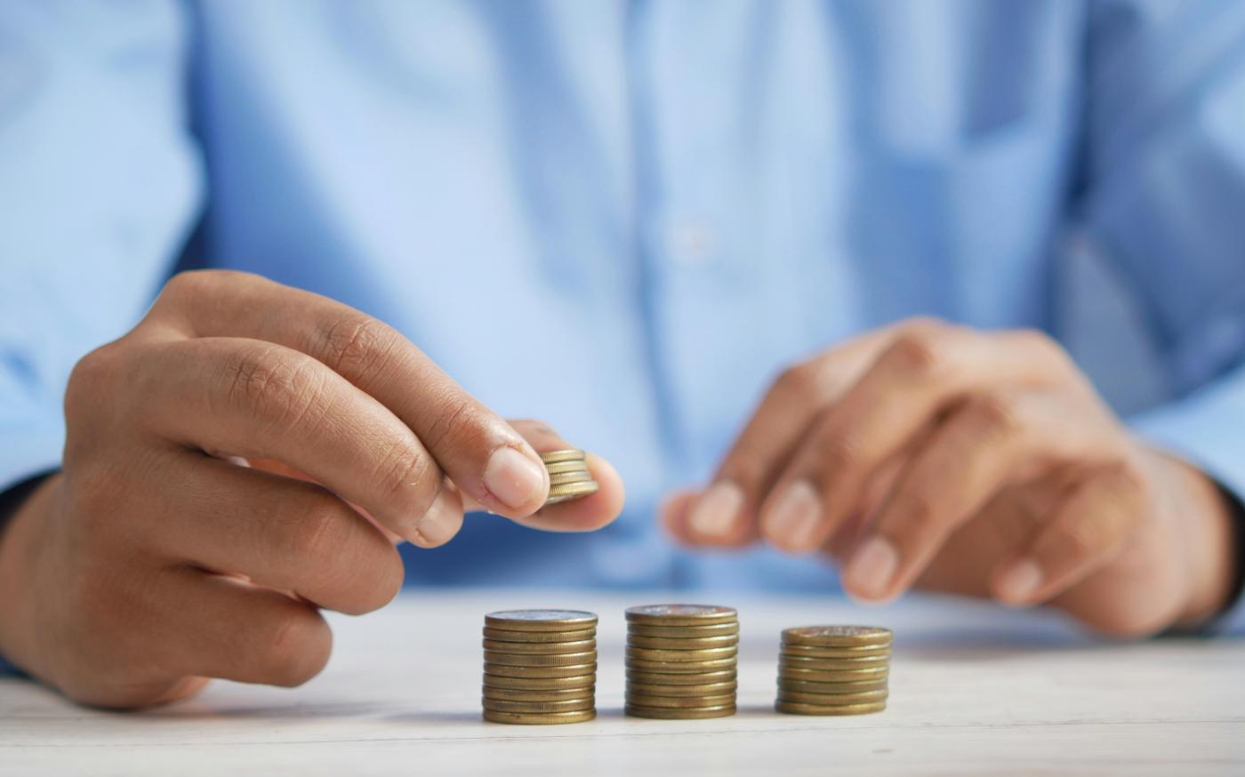 a person stacking coins on top of a table by Towfiqu barbhuiya courtesy of Unsplash.